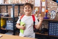 Little hispanic boy wearing student backpack and holding book at school class screaming proud, celebrating victory and success Royalty Free Stock Photo