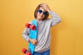 Little hispanic boy wearing sunglasses holding skate stressed and frustrated with hand on head, surprised and angry face Royalty Free Stock Photo