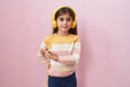 Little hispanic girl listening to music using headphones smiling cheerful pointing with hand and finger up to the side Royalty Free Stock Photo