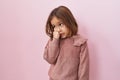 Little hispanic girl standing over pink background looking stressed and nervous with hands on mouth biting nails Royalty Free Stock Photo