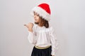 Little hispanic girl wearing christmas hat pointing thumb up to the side smiling happy with open mouth Royalty Free Stock Photo