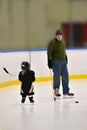 Little hockey girl is wearing in full equipment: helmet, glows, skates, stick. She is hold