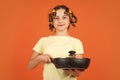 Little homemaker holding pan with ready meal. kid daily routine small girl making domestic work. girl with curlers in