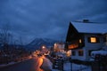 Little houses covered with snow and christmas lights at night.