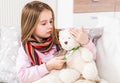 Little ill girl measuring teddy bear`s temperature Royalty Free Stock Photo