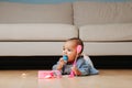 Little infant baby playing on the floor, eating doll head