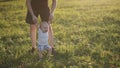 Little infant boy jumping on green grass with his father.