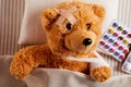 Little injured teddy bear lying sick in bed Royalty Free Stock Photo