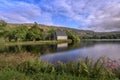 Little irish church on a peninsula in front of hills with blossoming flowers and fern - the St Finbarr`s Oratory