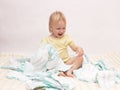 Little joyful girl playing with a pile of diapers on a white background, copy space, napkin