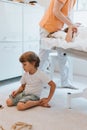Little kid boy brother plays on the floor while the doctor pediatrician and osteopath does physiological therapy for his older sis Royalty Free Stock Photo