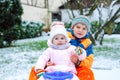 Little kid boy and cute toddler girl sitting together on sledge. Siblings, brother and baby sister enjoying sleigh ride Royalty Free Stock Photo