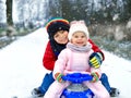 Little kid boy and cute toddler girl sitting together on sledge. Siblings, brother and baby sister enjoying sleigh ride Royalty Free Stock Photo