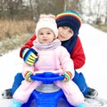 Little kid boy and cute toddler girl sitting together on sledge. Siblings, brother and baby sister enjoying sleigh ride Royalty Free Stock Photo