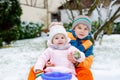 Little kid boy and cute toddler girl sitting together on sledge. Siblings, brother and baby sister enjoying sleigh ride