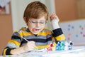 Little kid boy drawing with colorful watercolors