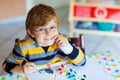 Little kid boy drawing with colorful watercolors