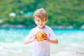 Little kid boy drinking coconut juice on tropical beach Royalty Free Stock Photo