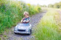 Little kid boy driving big toy car with a bear, outdoors. Royalty Free Stock Photo