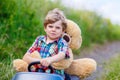 Little kid boy driving big toy car with a bear, outdoors. Royalty Free Stock Photo