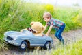 Little kid boy driving big toy car with a bear, outdoors. Royalty Free Stock Photo