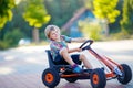 Little kid boy driving pedal race car in summer