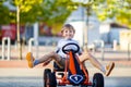 Little kid boy driving pedal race car in summer