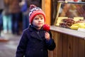 Little kid boy eating crystalized apple on Christmas market Royalty Free Stock Photo