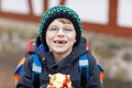 Little kid boy with eye glasses walking from the school and eating apple