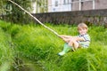 Little kid boy fishing on river with selfmade fishing rod Royalty Free Stock Photo
