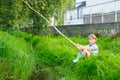 Little kid boy fishing on river with selfmade fishing rod Royalty Free Stock Photo