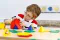 Little kid boy with glasses playing with lolorful plastic elements kit in school or preschool nursery. Happy child