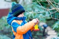 Little kid boy hanging bird house on tree for feeding in winter Royalty Free Stock Photo