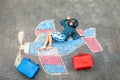 Little kid boy having fun with with airplane picture drawing with colorful chalks on asphalt. Child painting with chalk