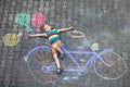 Little kid boy having fun with bicycle chalks picture on ground Royalty Free Stock Photo