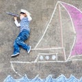 Little kid boy having fun with ship picture drawing with chalk Royalty Free Stock Photo
