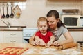 Little kid boy helps mother to cook ginger biscuit. Happy family mom and child in weekend morning at home. Relationship.