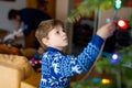 Little kid boy and his dad taking down holiday decorations from Christmas tree. Father on background. Family after Royalty Free Stock Photo