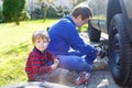 Little kid boy and his father changing wheel on car Royalty Free Stock Photo