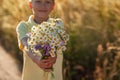 Little kid boy holding bouquet of fields camomile flowers in summer day. Child giving flowers Royalty Free Stock Photo