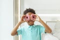 Little kid boy looking through pink donuts. Child holding two donuts near eyes like glasses and having fun Royalty Free Stock Photo