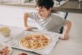 Little kid boy making pizza sitting at the table on the kitchen. Children helping in cooking lifestyle image Royalty Free Stock Photo