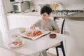 Little kid boy making pizza sitting at the table on the kitchen. Children helping in cooking lifestyle image Royalty Free Stock Photo