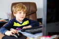 Little kid boy making school homework on computer notebook. Happy healthy child searching information on internet. New Royalty Free Stock Photo