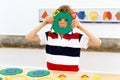 Little kid boy playing with lots of colorful plastic blocks kit in school or preschool nursery. Happy child having fun