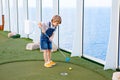 Little kid boy playing mini golf on a cruise liner. Royalty Free Stock Photo