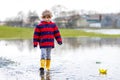 Little kid boy playing with paper boat by puddle Royalty Free Stock Photo