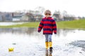 Little kid boy playing with paper boat by puddle Royalty Free Stock Photo