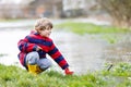 Little kid boy playing with paper boat by puddle Royalty Free Stock Photo