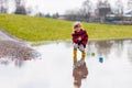 Little kid boy playing with paper ship by puddle Royalty Free Stock Photo